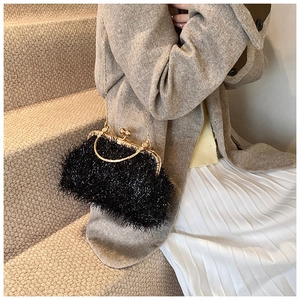 Detail of elegant black fringe shell bag with gold metal frame and handle for formal events