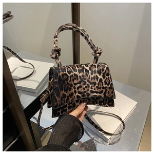 Close-up of leopard print handbag featuring a curved base and dual knotted handles