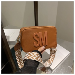 Close-up of brown Saffiano leather camera bag with SM logo and geometric wide strap