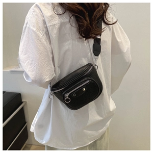 Detail of black lychee grain leather crossbody bag with silver rings and studs on a model