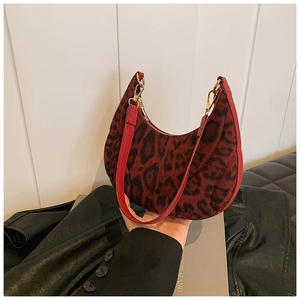 Macro shot of red leopard print knit texture and red leather trim on hobo bag