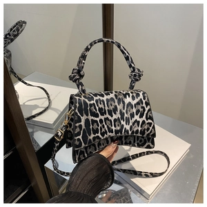 Detail shot of the knotted handle and leopard print texture on this stylish crossbody bag