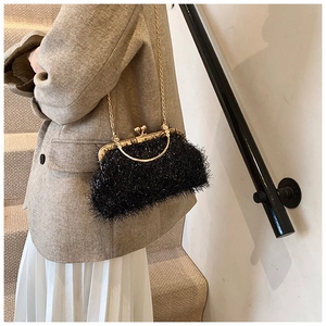 Close-up of black plush shell bag with gold metal handle and chain in street style
