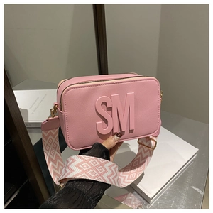 Detail of pink camera bag with SM logo lettering and geometric patterned wide strap