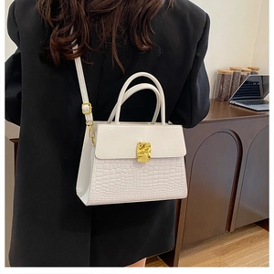 Detailed view of white crocodile pattern shoulder bag with golden lock on a female model