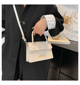 Detailed view of cream lychee-textured crossbody bag with FASHION lettering and strap