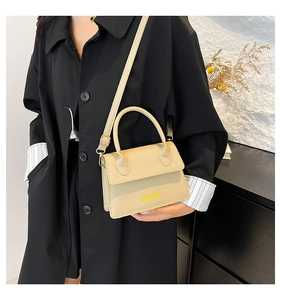 Detail view of beige mini crossbody bag with a textured finish and fashion lettering