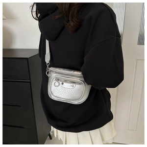 Close-up of silver textured motorcycle crossbody bag with metallic rivets and zippers