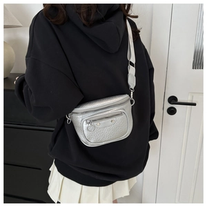 Detail of silver textured crossbody bag featuring metallic rivets and wide strap