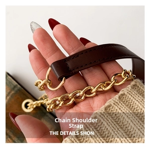 Detail of a brown leather shoulder strap with golden metal chain links for handbags