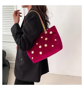 Detail of fuchsia velvet tote bag with gold starburst studs and chain strap on shoulder