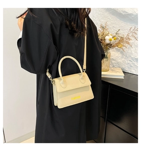 Detail of a beige textured leather crossbody bag with FASHION lettering in a home setting