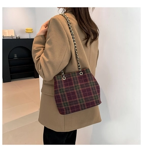 Detail view of plaid wool shoulder bag with gold chain strap on a stylish model