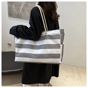 Detail of large striped canvas tote bag featuring thick cotton rope handles and metal eyelets