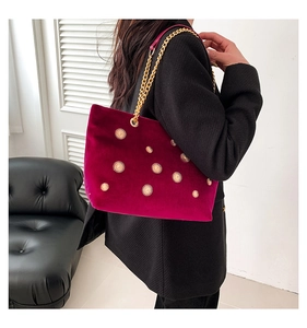 Detail of burgundy velvet tote bag with gold sunflower studs and chain strap