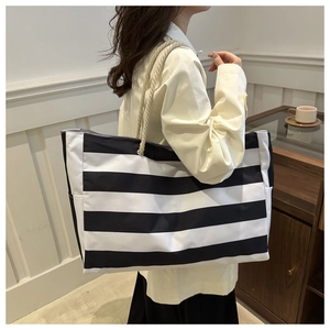 Detail of a large capacity striped tote bag with sturdy rope handles for daily commute