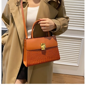 Detailed view of the vintage crocodile texture and modern gold buckle on the leather handbag