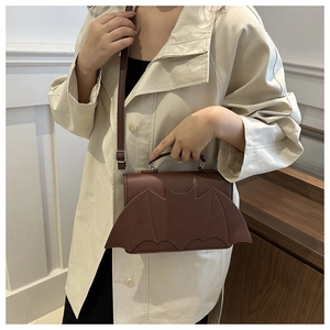 Detail of dark brown bat-shaped PU leather bag with adjustable strap and top handle