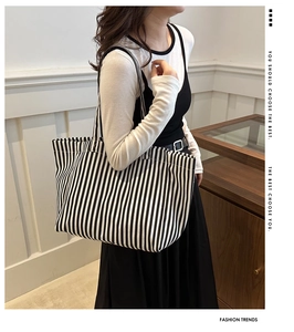 Détail d'un grand sac cabas en toile à rayures noires et blanches porté par un mannequin