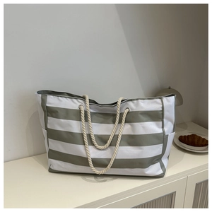 Detail of grey striped canvas tote bag showing thick rope handles and side pocket