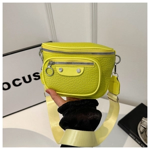 Detail of neon green crocodile texture crossbody bag with silver zippers and wide strap
