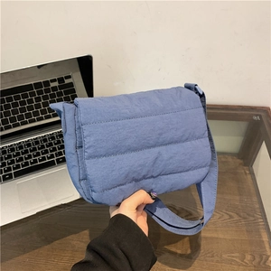 Minimalist blue quilted crossbody bag with nylon padded texture and wide shoulder strap