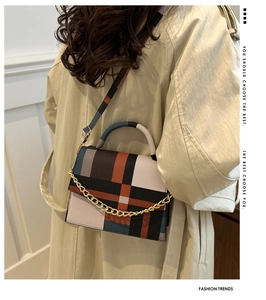Detail of color-block geometric pattern bag with chain on a beige trench coat