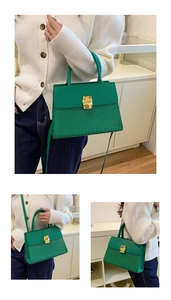 Detail view of emerald green crocodile embossed crossbody bag with gold buckle