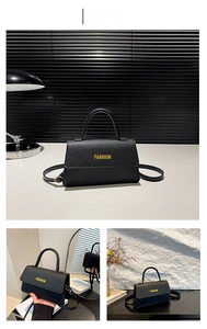 Detail of black lychee grain leather handbag with yellow FASHION text and top handle