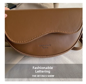 Detail view of brown vintage saddle bag featuring white contrast stitching and logo