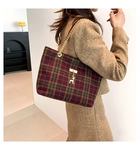 Close-up of a plaid wool tote bag featuring a gold chain and a small deer metal charm