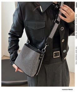 Detail of studded bucket bag with sparkling rhinestones and chic striped wide shoulder strap