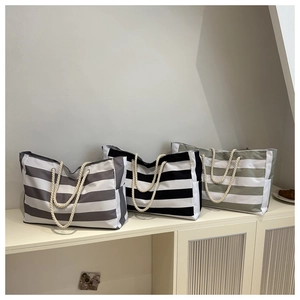 Detailed view of three striped canvas tote bags in grey, black, and olive green colors