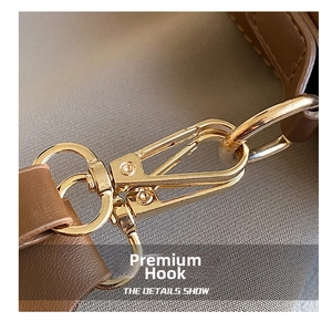 Macro shot of polished gold-plated hardware hooks on brown leather saddle bag strap