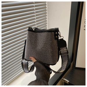 Detail of black bucket bag with silver studs and wide chevron woven shoulder strap