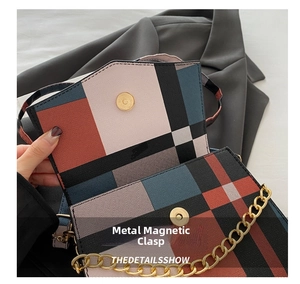 Detail of color-block crossbody bag featuring gold magnetic snap and metal chain strap