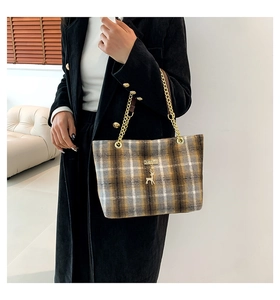 Detail of wool fabric plaid handbag featuring a gold deer charm and chain shoulder strap