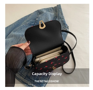 Interior storage of black faux leather crossbody bag with red cherry prints and metal clasp