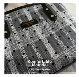 Detail of black and white lace mesh fabric with gold rivets on a tote bag