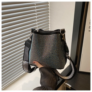 Detail of black bucket bag with rainbow rhinestones and herringbone wide strap