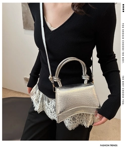 Close-up of silver crocodile pattern handbag with hourglass curved base on a model
