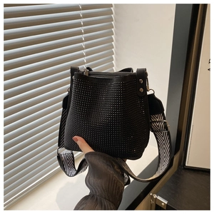 Detail of black rhinestone bucket bag with a stylish black and white wave pattern strap