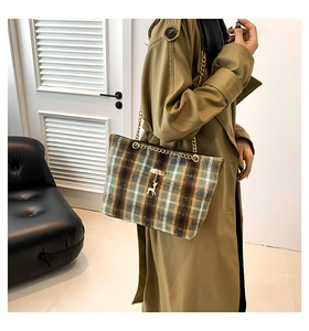 Close-up of green plaid tote bag with gold chain strap and deer metal pendant