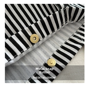 Détail du fermoir magnétique doré sur le tissu du sac cabas en toile rayée
