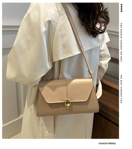 Detail of beige faux leather underarm bag featuring a stylish golden oval buckle closure