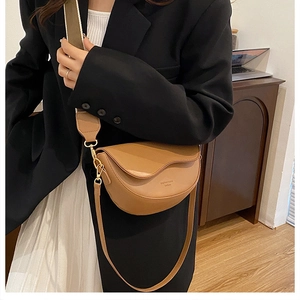 Detail of camel leather saddle bag with wide fabric strap on model in home setting