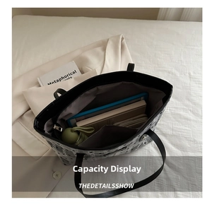 Top-down view of a spacious black tote bag interior holding a tablet, books, and umbrella