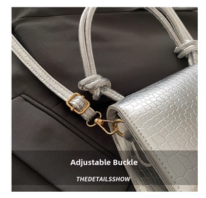 Close-up of silver crocodile embossed leather texture with gold adjustable buckle and hook