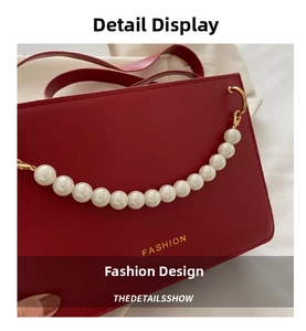 Detail of red leather bag with gold FASHION lettering and elegant pearl chain handle
