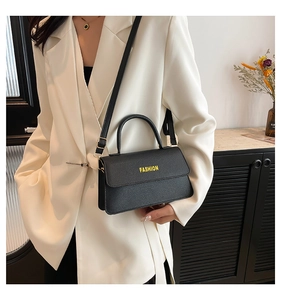 Detail of black pebbled leather tote bag with yellow FASHION lettering and gold metal hardware